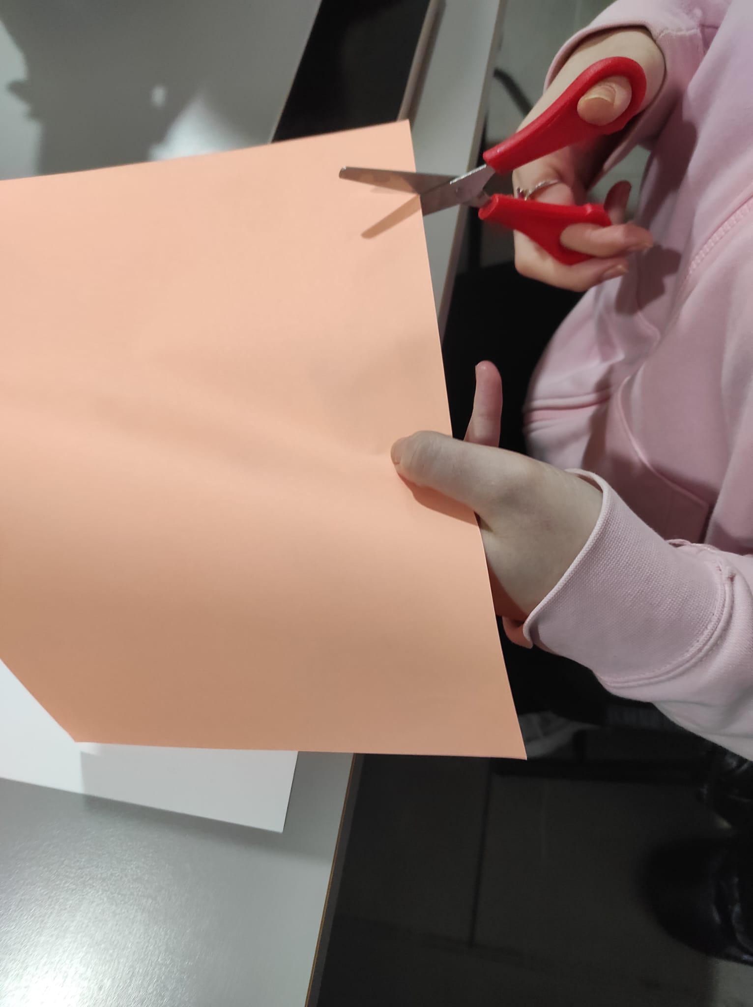 Mani impegnate a ritagliare un cartoncino arancione per le decorazioni