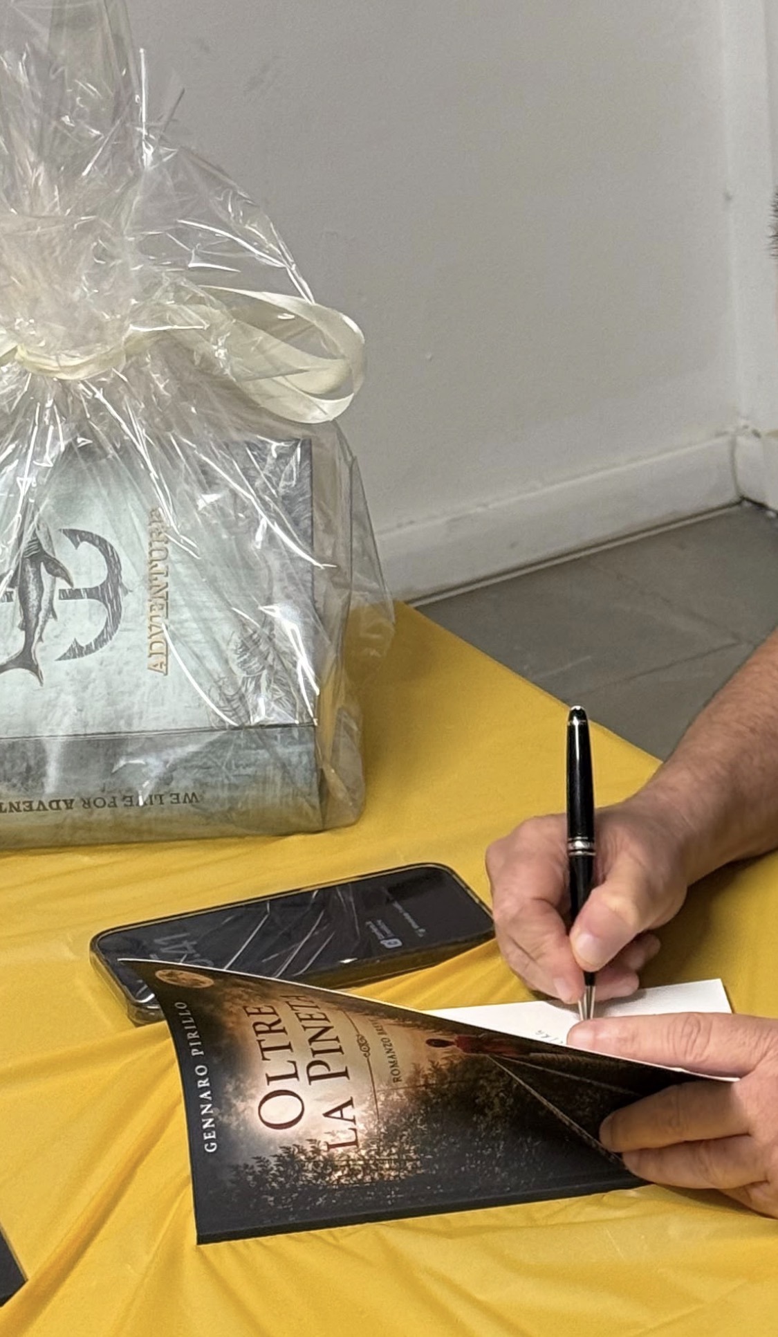 Le mani dell’autore mentre scrive una dedica su Oltre la pineta